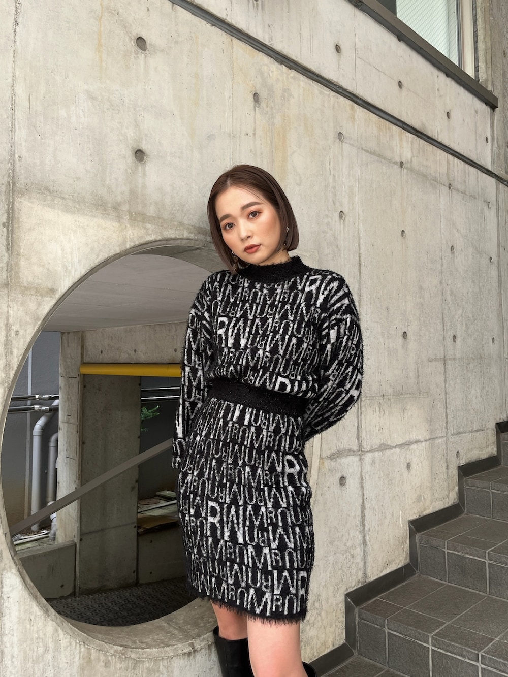 グレー系のダウンベスト、ブラック系のニット/セーター、ブラック系のスカートを着用したレディースの秋コーディネートの6枚目の写真