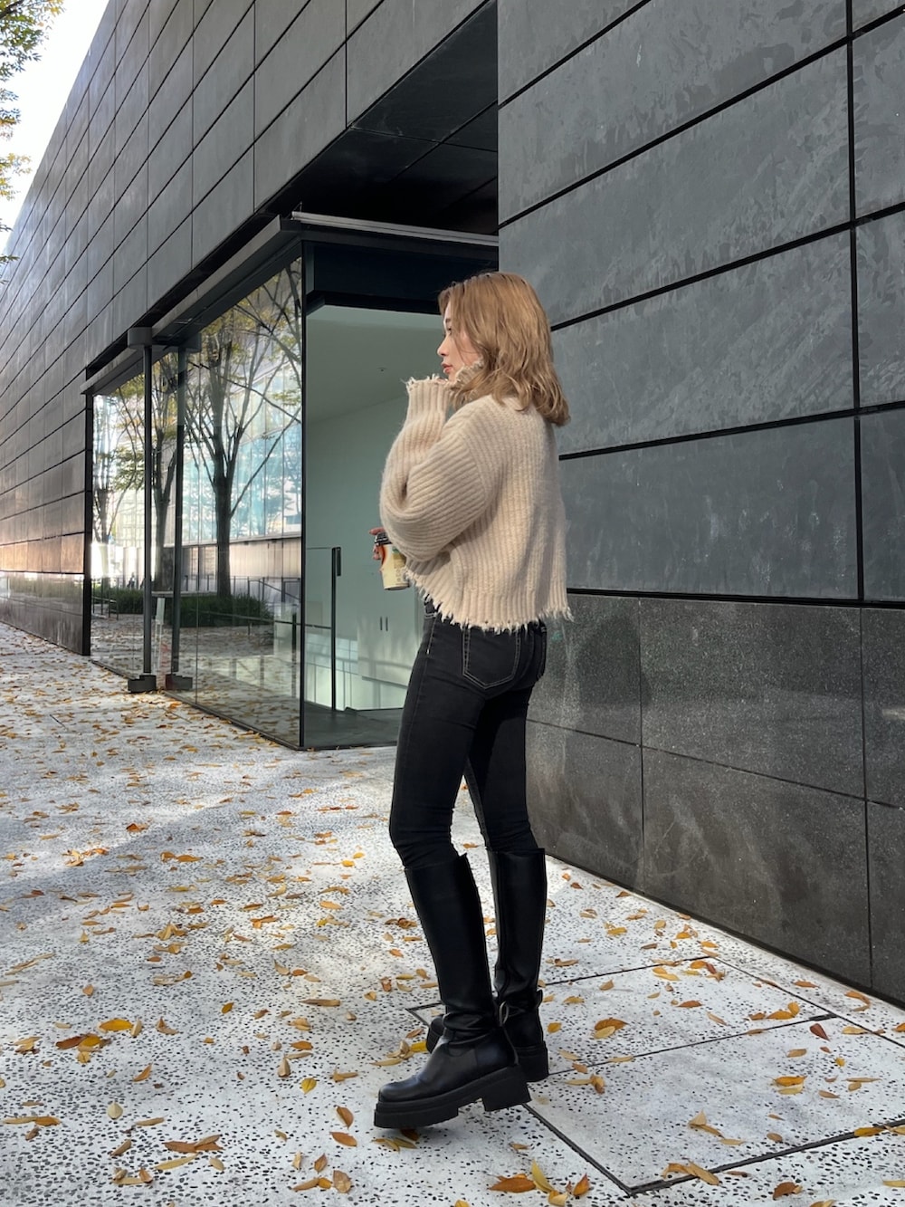 ホワイト系のニット/セーター、ブラック系のハンドバッグ、ブラック系のブーツを着用したレディースの秋コーディネートの3枚目の写真