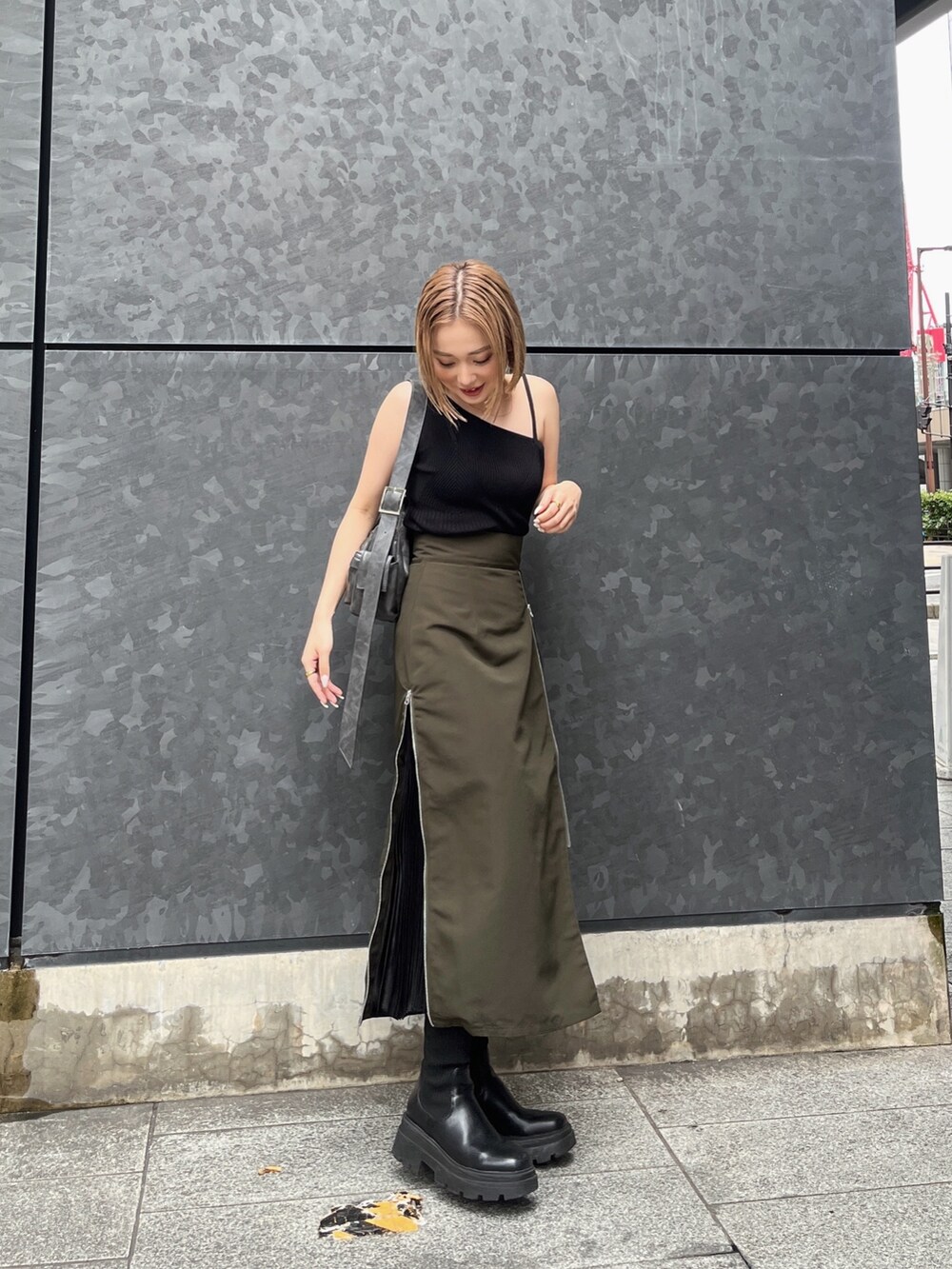 ブラック系のニット/セーター、グリーン系のスカート、グレー系のショルダーバッグを着用したレディースの夏コーディネートの2枚目の写真