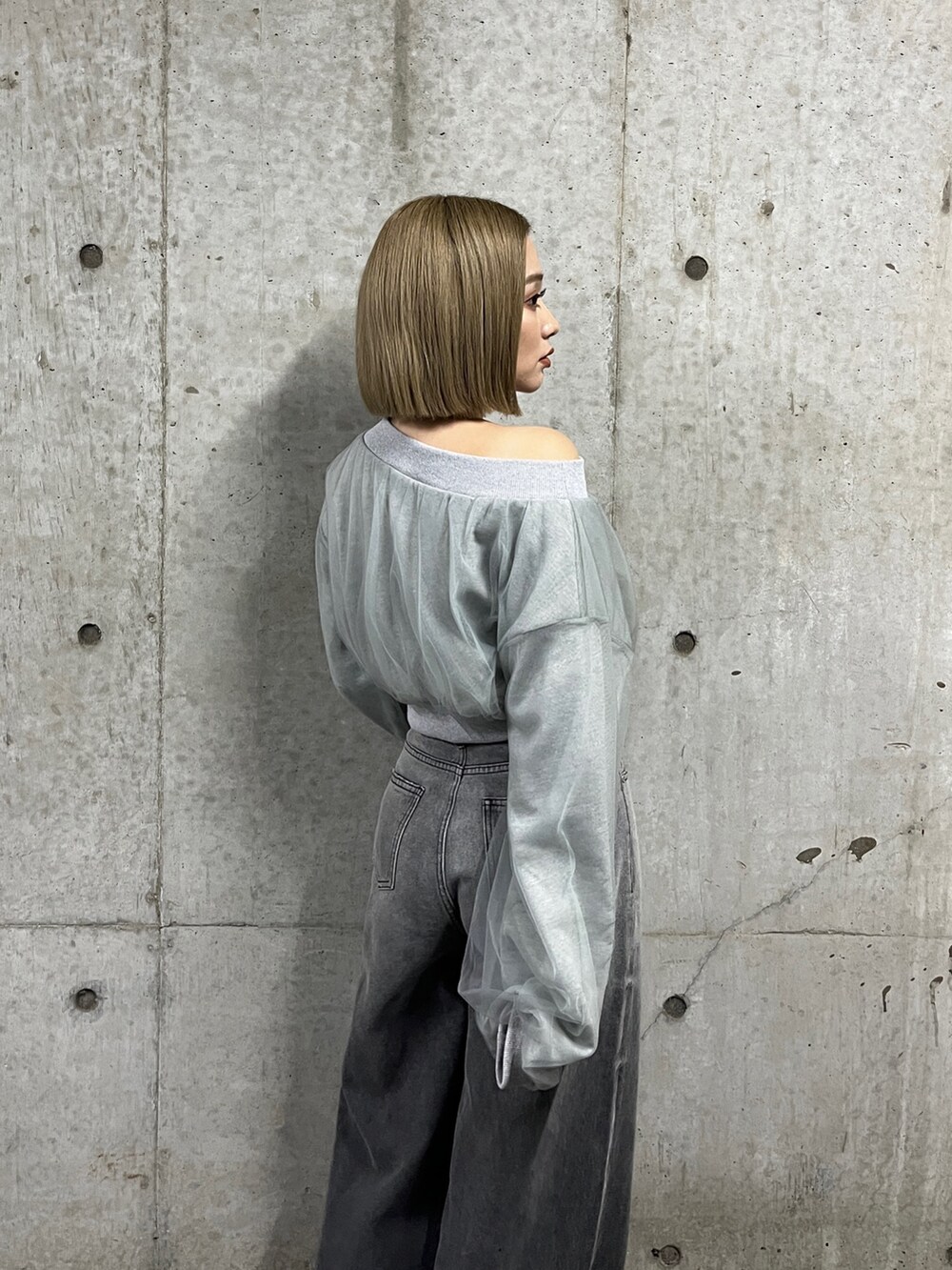 グレー系のスウェット、ブラック系のデニムパンツ、シルバー系のパンプスを着用したレディースの冬コーディネートの8枚目の写真