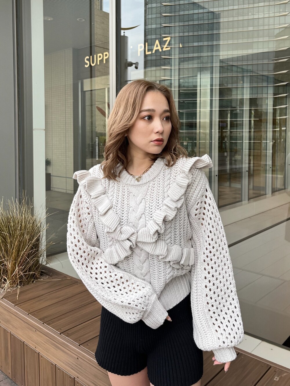 グレー系のニット/セーター、ブラック系のスウェットパンツ、ブラック系のブーツを着用したレディースの冬コーディネートの5枚目の写真