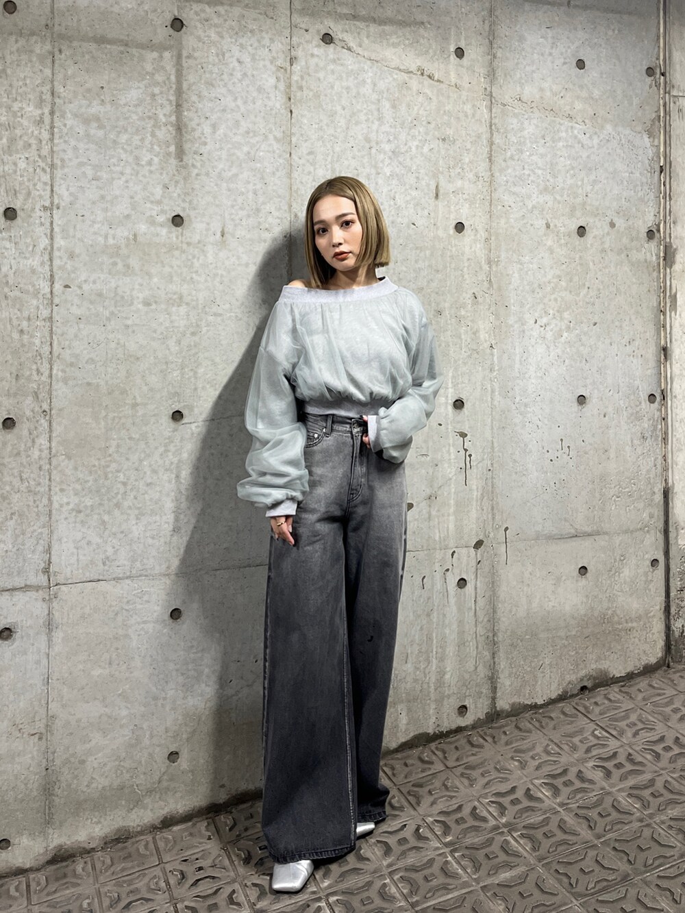 グレー系のスウェット、ブラック系のデニムパンツ、シルバー系のパンプスを着用したレディースの冬コーディネートの2枚目の写真