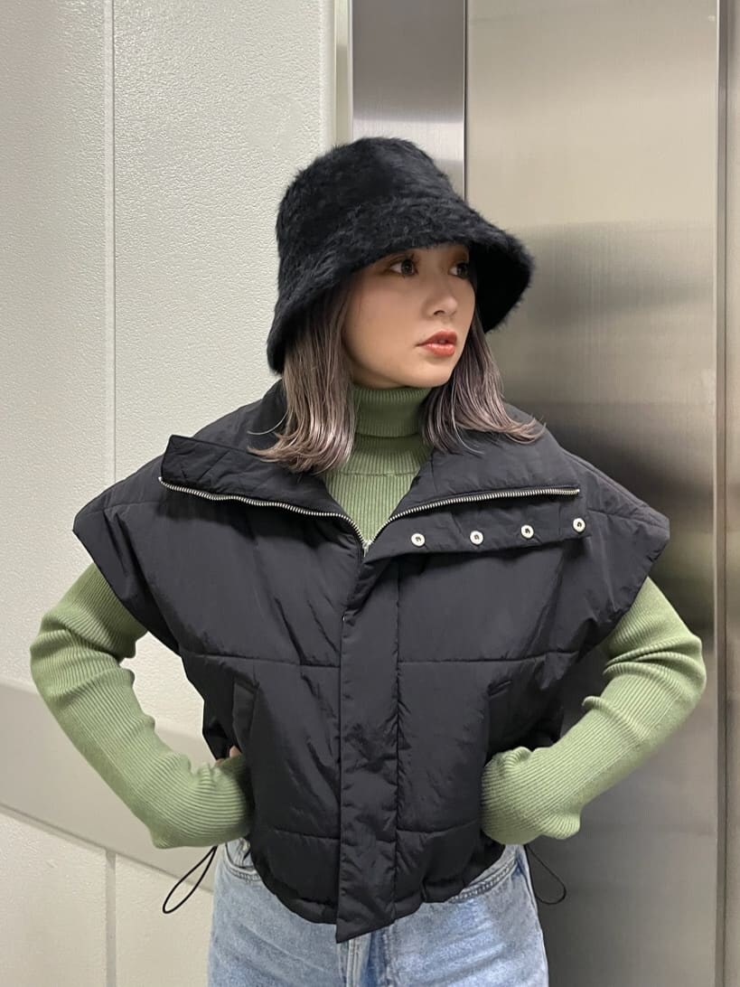 ブラック系のダウンベスト、グリーン系のニット/セーター、ブラック系のハットを着用したレディースの秋コーディネートの4枚目の写真