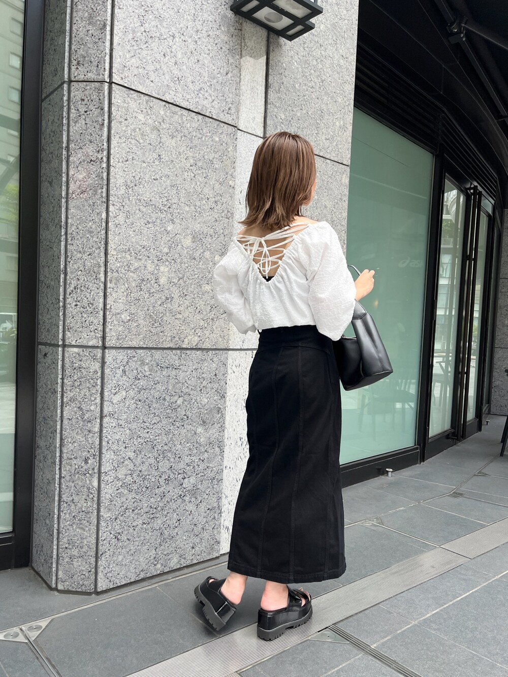ホワイト系のシャツ/ブラウス、ブラック系のスカート、ブラック系のサンダルを着用したレディースの夏コーディネートの3枚目の写真