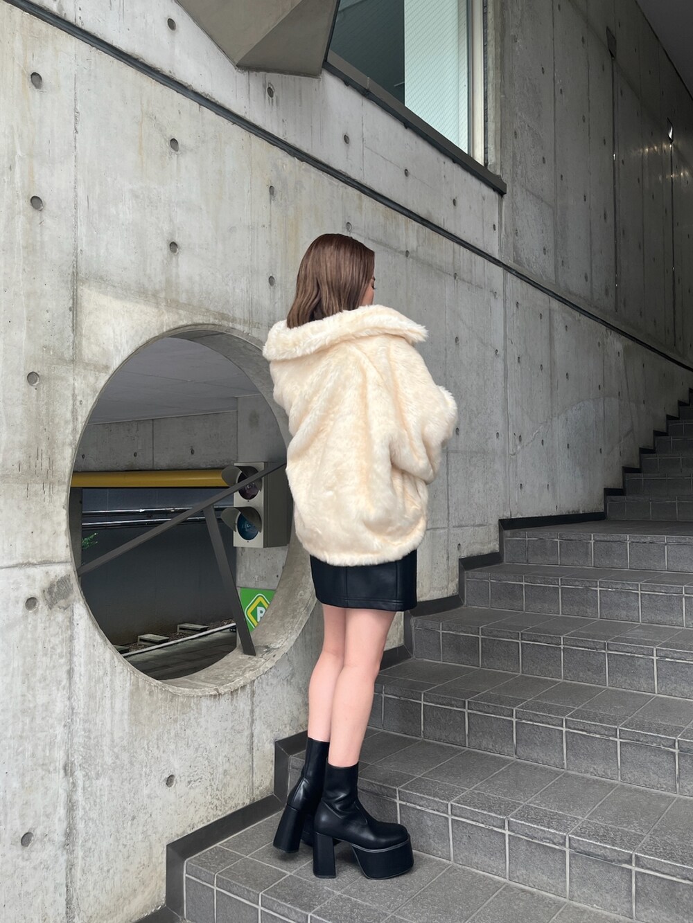 ホワイト系のブルゾン、ブルー系のニット/セーター、ブラック系のブーツを着用したレディースの秋コーディネートの2枚目の写真