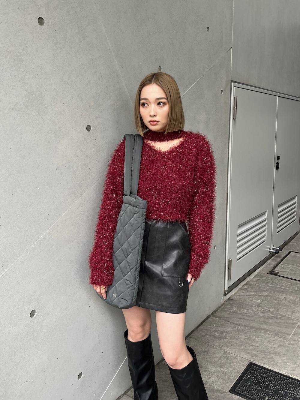 レッド系のニット/セーター、ブラウン系のスカート、ブラック系のブーツを着用したレディースの冬コーディネートの5枚目の写真