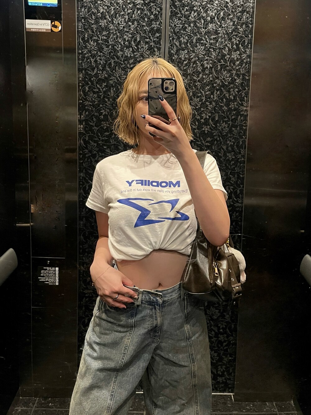 ホワイト系のTシャツ/カットソー、その他のデニムパンツ、ブラウン系のハンドバッグを着用したレディースの夏コーディネートの2枚目の写真