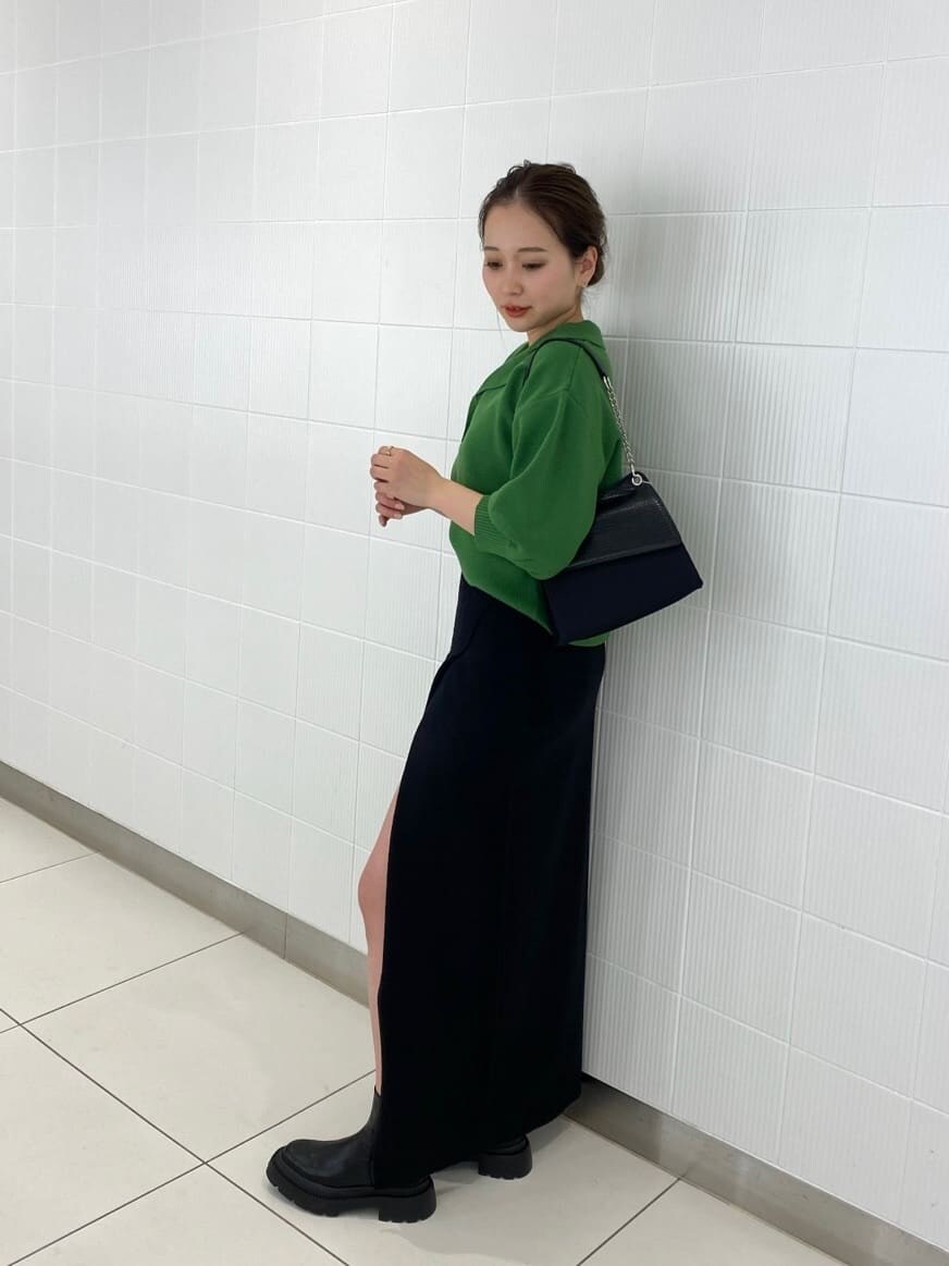 ブラック系のブーツ、ブラック系のハンドバッグ、ブラック系のスカートを着用したレディースの春コーディネートの3枚目の写真