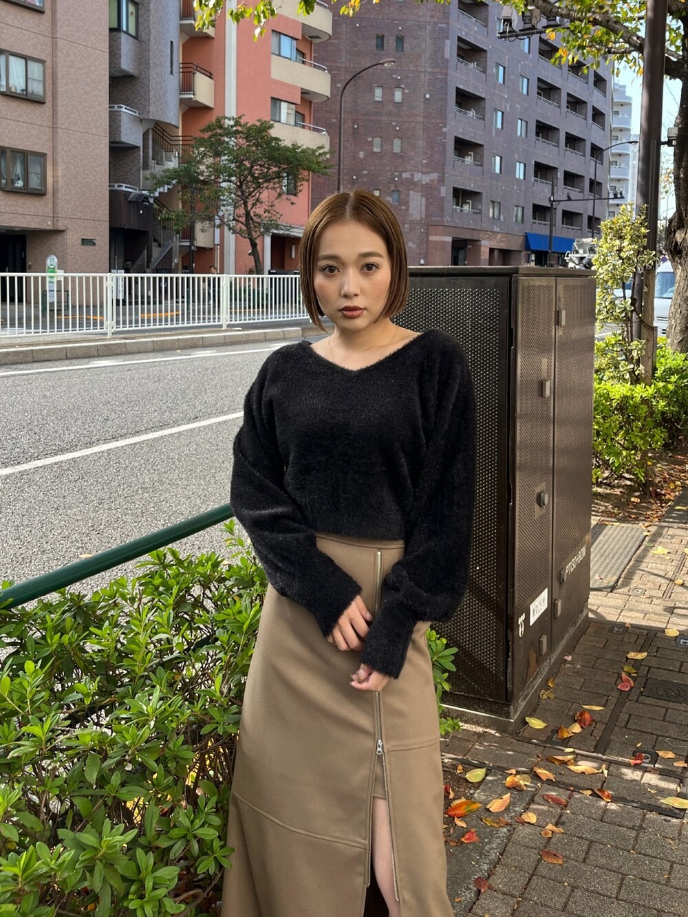 ブラック系のニット/セーター、ベージュ系のスカート、ブラック系のブーツを着用したレディースの秋コーディネートの2枚目の写真