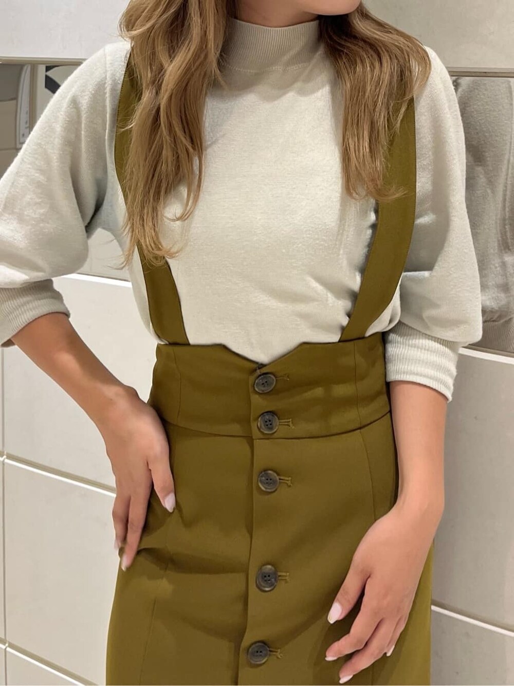 イエロー系のワンピース、ブラック系のブーツ、ホワイト系のニット/セーターを着用したレディースの秋コーディネートの6枚目の写真