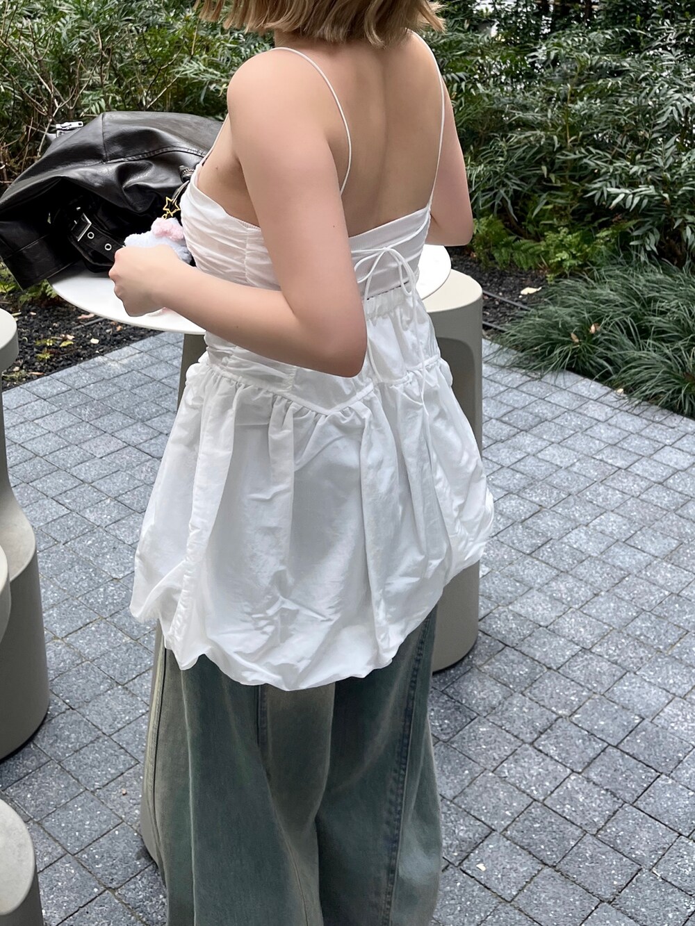 ホワイト系のキャミソール、ブルー系のデニムパンツ、ブラウン系のハンドバッグを着用したレディースの春コーディネートの5枚目の写真