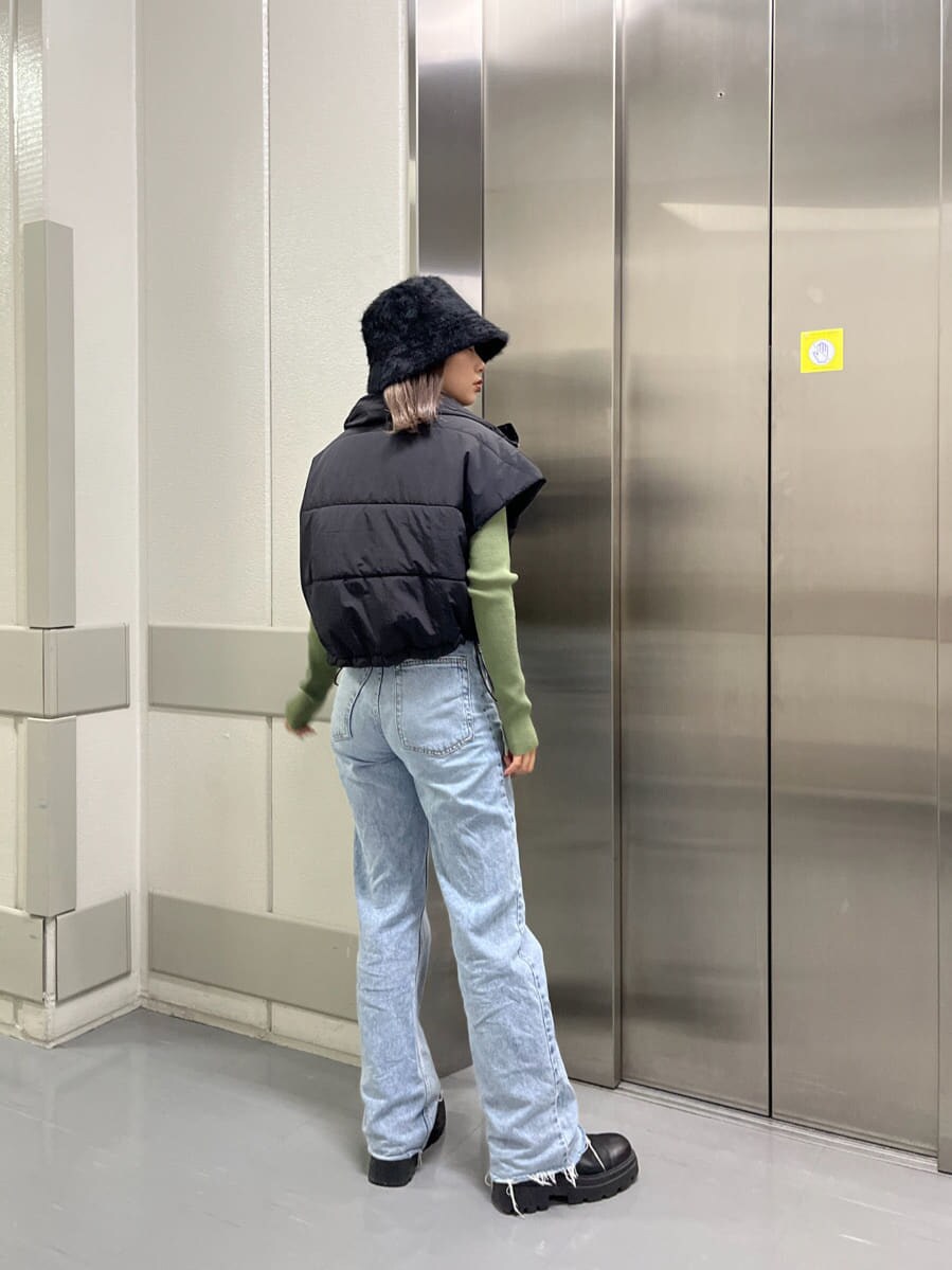 ブラック系のダウンベスト、グリーン系のニット/セーター、ブラック系のハットを着用したレディースの秋コーディネートの3枚目の写真