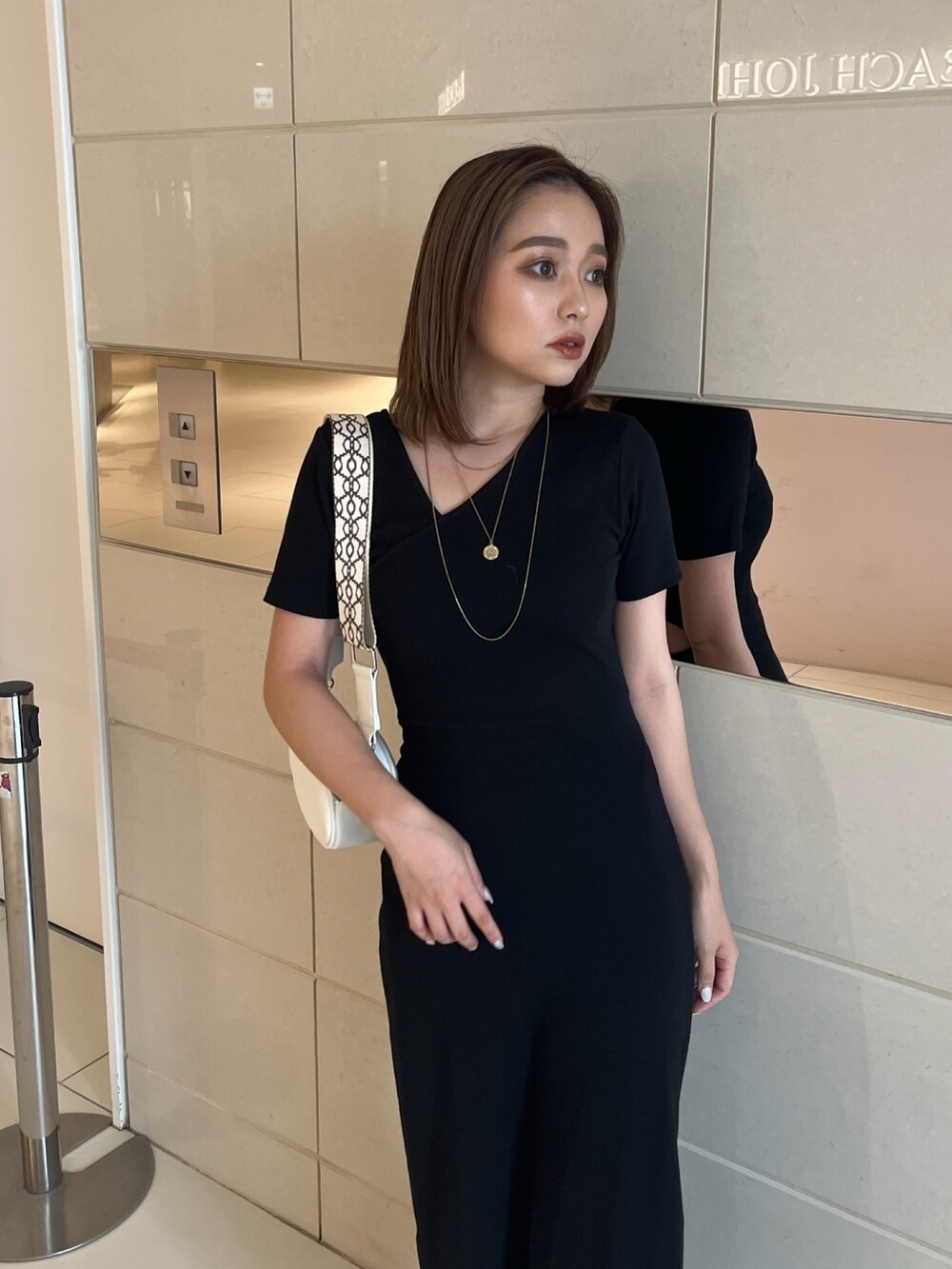 ブラック系のワンピース、ホワイト系のショルダーバッグ、ブラック系のサンダルを着用したレディースの夏コーディネートの4枚目の写真