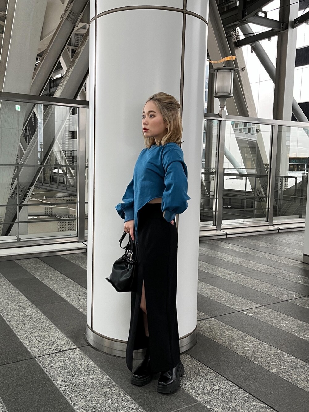 ブルー系のTシャツ/カットソー、ブラック系のスカート、ブラック系のハンドバッグを着用したレディースの冬コーディネートの2枚目の写真