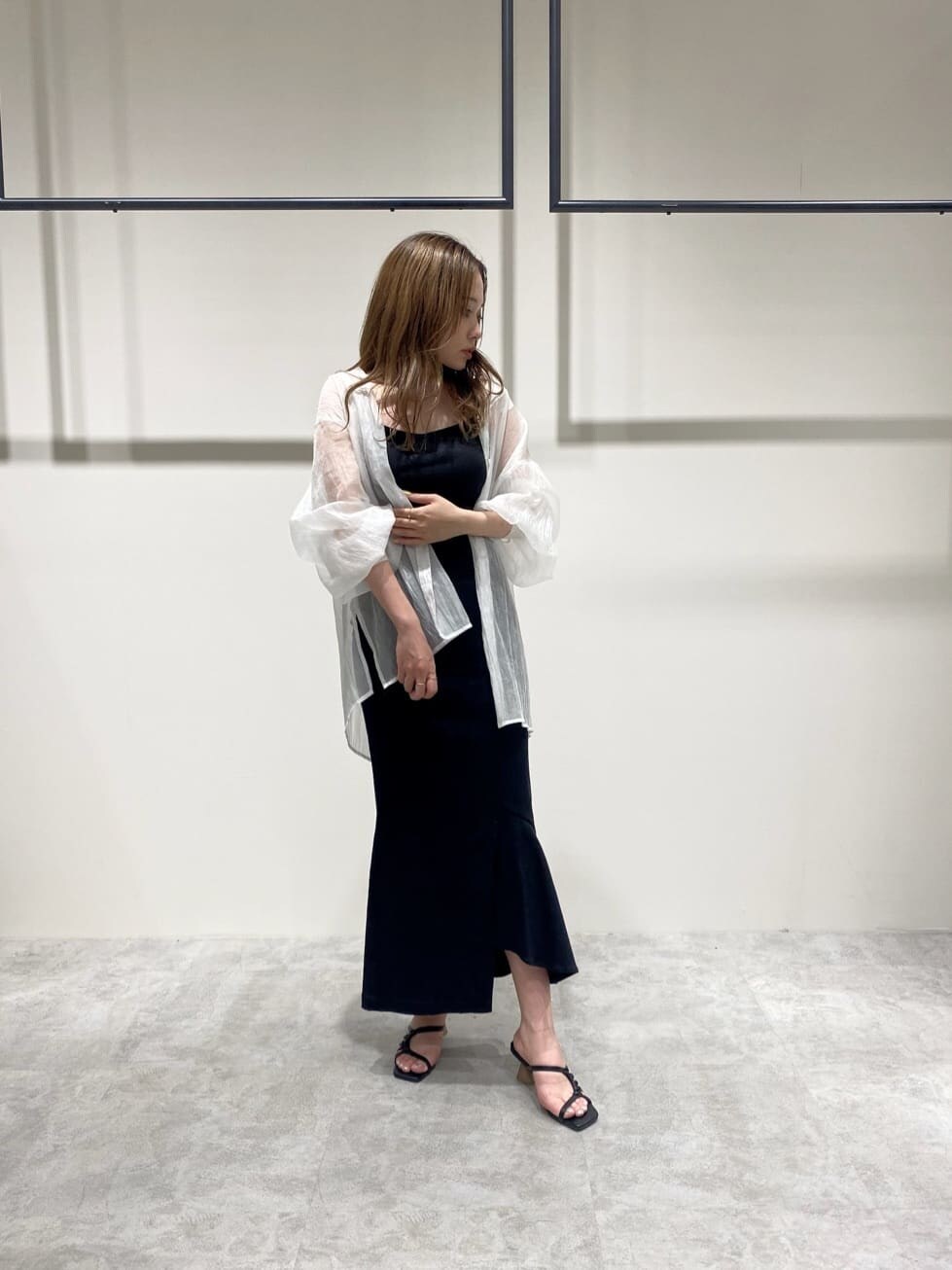 ブラック系のスカート、ホワイト系のシャツ/ブラウス、ブラック系のサンダルを着用したレディースの春コーディネートの2枚目の写真