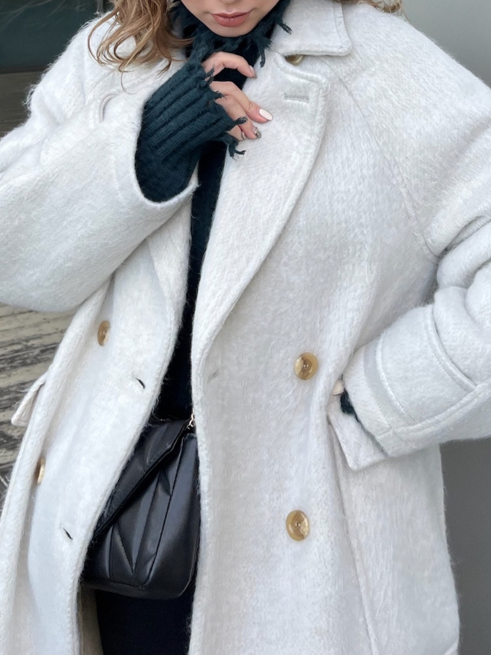 ホワイト系のチェスターコート、グリーン系のニット/セーター、ブラック系のブーツを着用したレディースの冬コーディネートの7枚目の写真