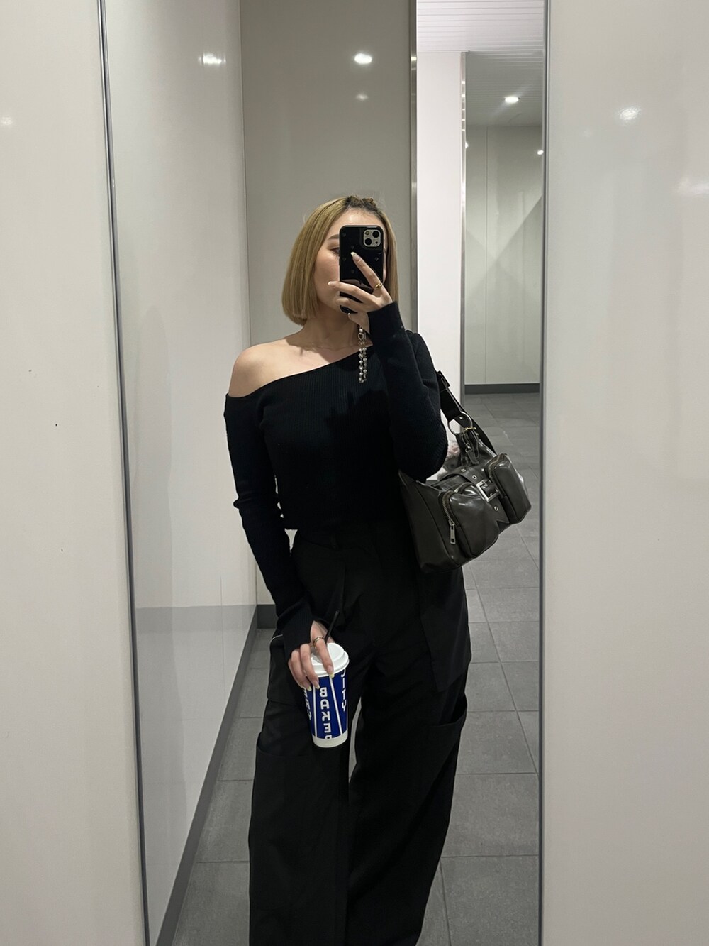 ブラック系のニット/セーター、ブラック系のスラックス、ブラウン系のハンドバッグを着用したレディースの春コーディネートの2枚目の写真