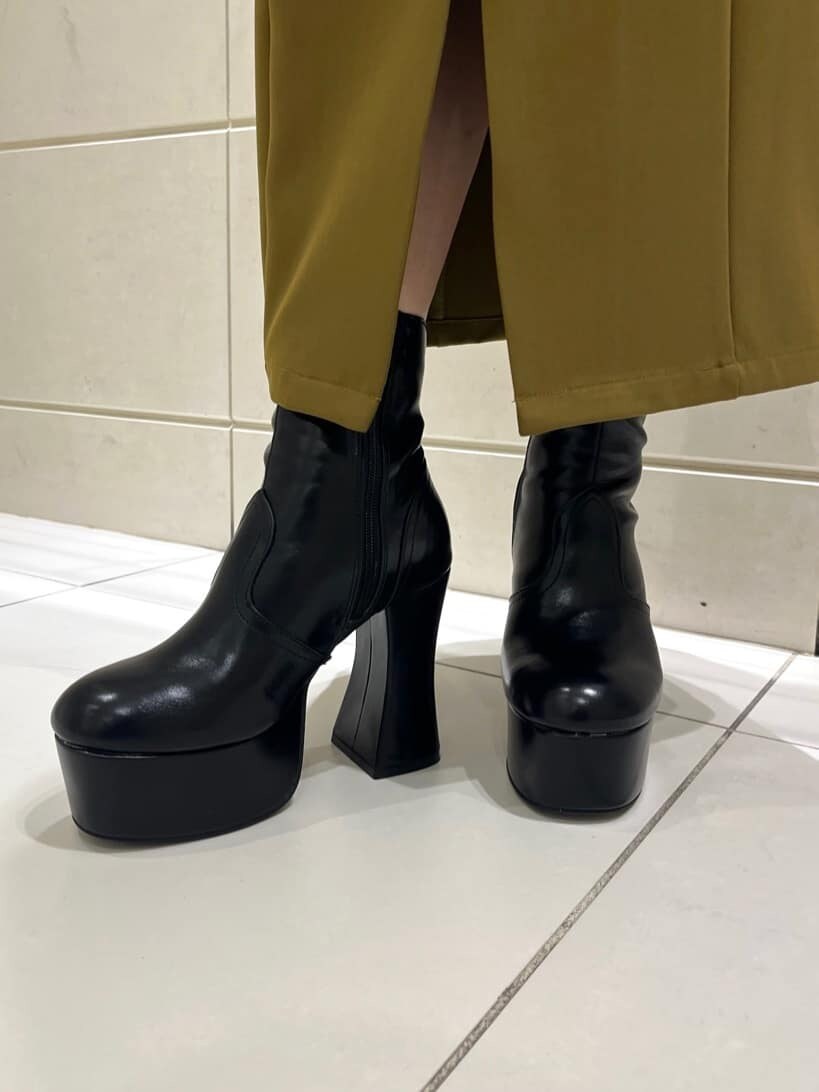 イエロー系のワンピース、ブラック系のブーツ、ホワイト系のニット/セーターを着用したレディースの秋コーディネートの9枚目の写真