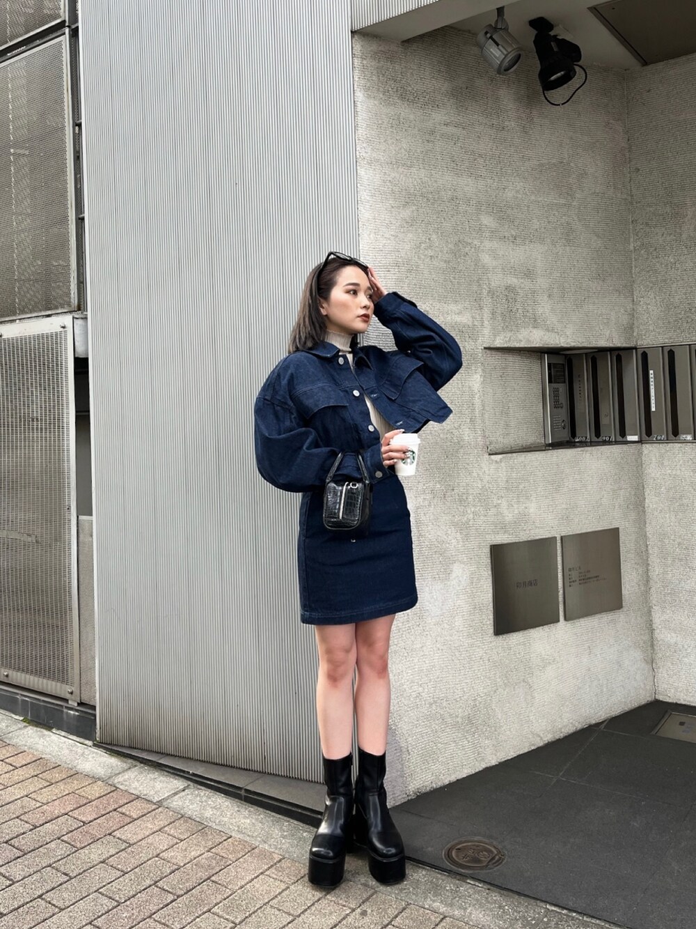 ブラック系のボストンバッグ、ブラック系のブーツ、ブルー系のデニムジャケットを着用したレディースの夏コーディネートの2枚目の写真