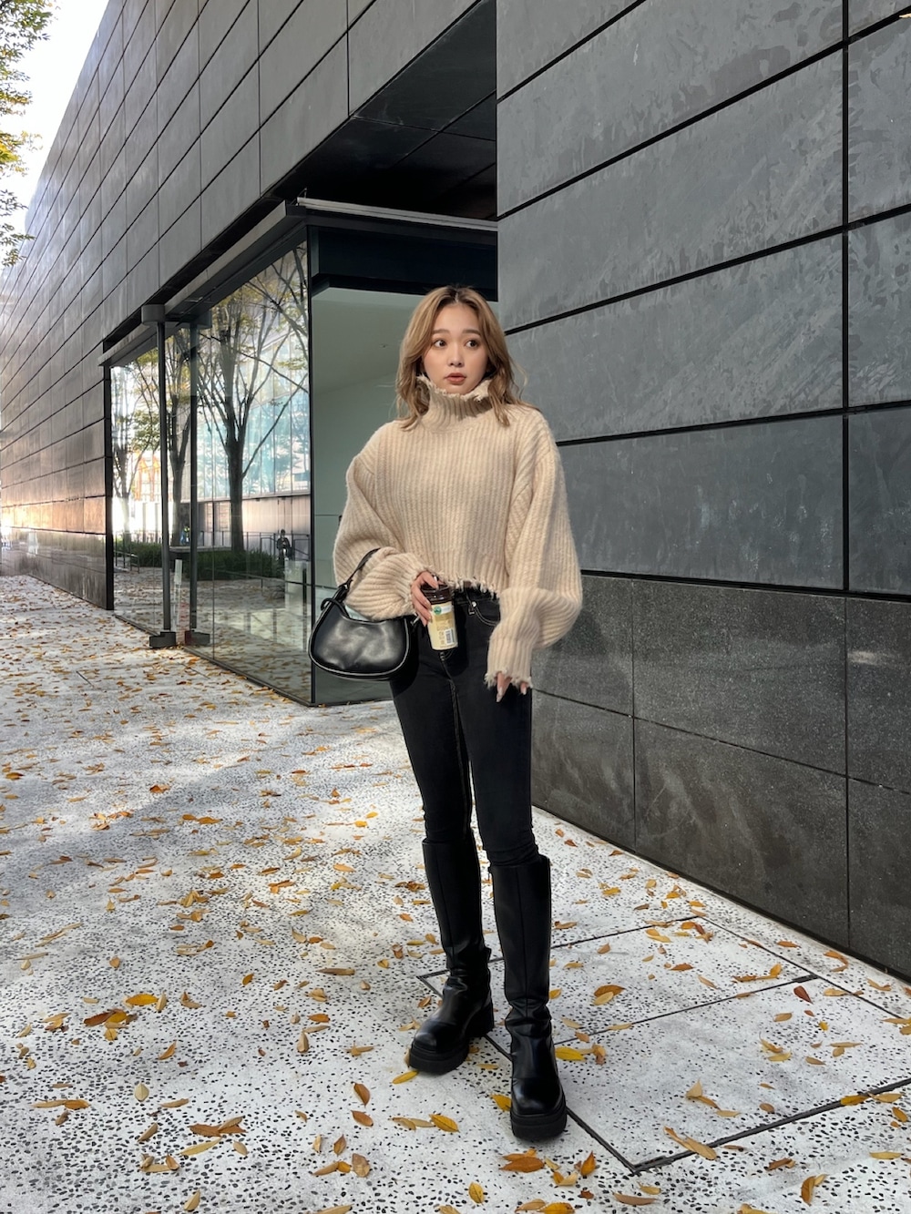 ホワイト系のニット/セーター、ブラック系のハンドバッグ、ブラック系のブーツを着用したレディースの秋コーディネートの2枚目の写真