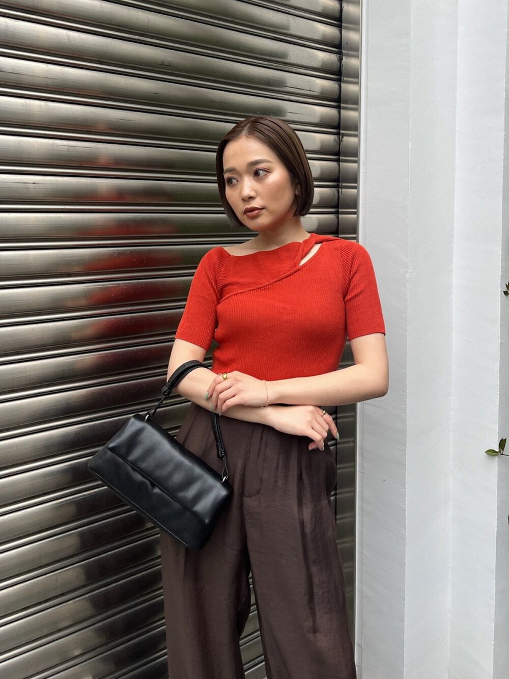 オレンジ系のニット/セーター、ブラウン系のその他パンツ、ブラック系のサンダルを着用したレディースの夏コーディネートの5枚目の写真