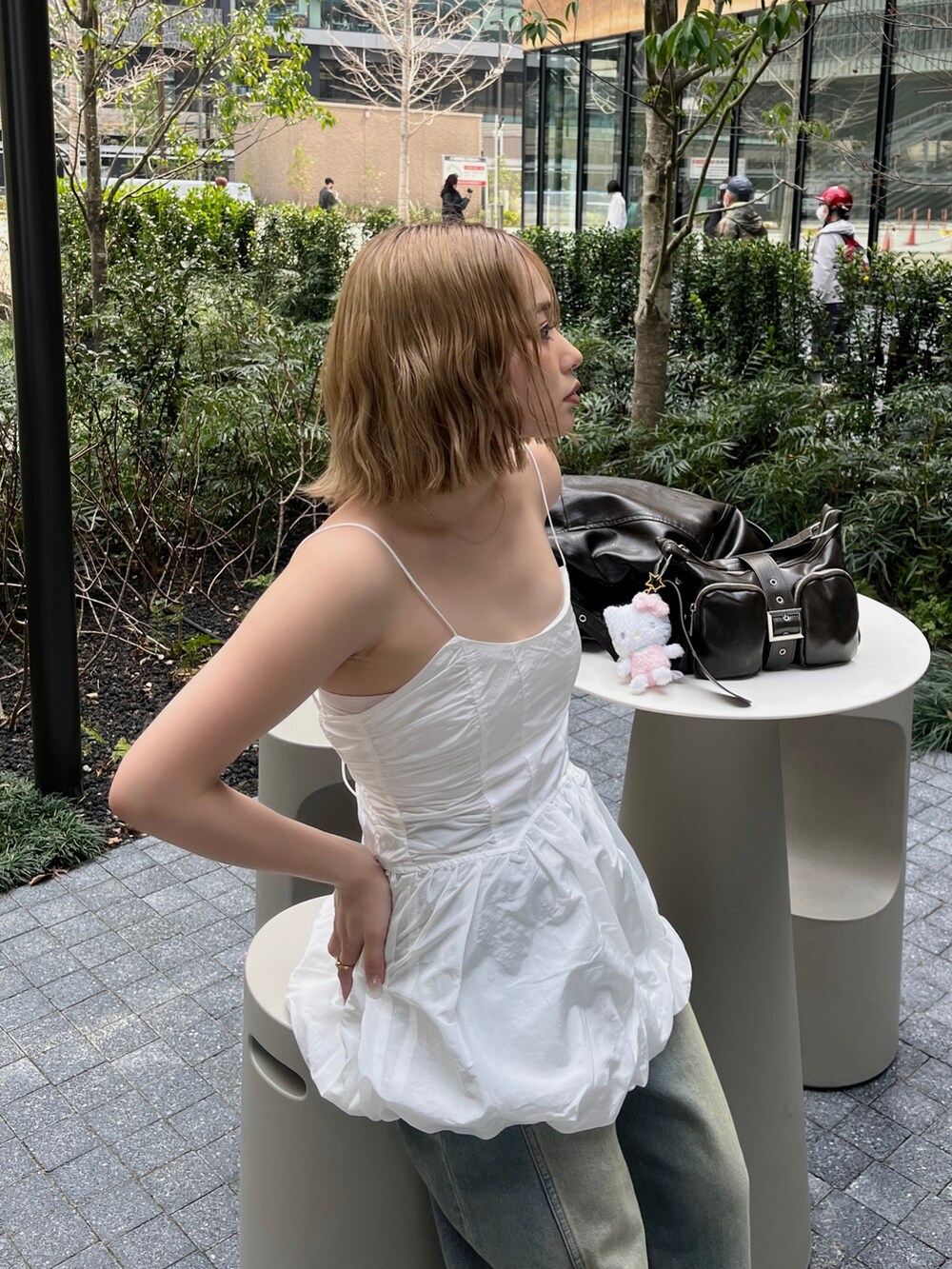 ホワイト系のキャミソール、ブルー系のデニムパンツ、ブラウン系のハンドバッグを着用したレディースの春コーディネートの3枚目の写真