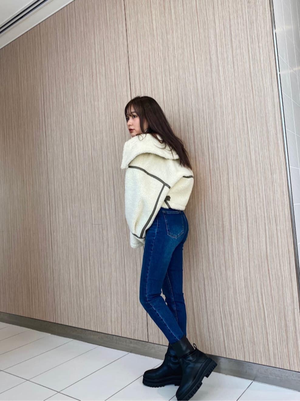 ブルー系のデニムパンツ、ブラック系のブーツ、ホワイト系のブルゾンを着用したレディースの冬コーディネートの3枚目の写真