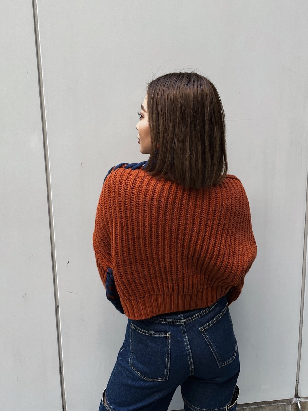 オレンジ系のニット/セーター、ブルー系のデニムパンツ、ブラック系のブーツを着用したレディースの冬コーディネートの3枚目の写真