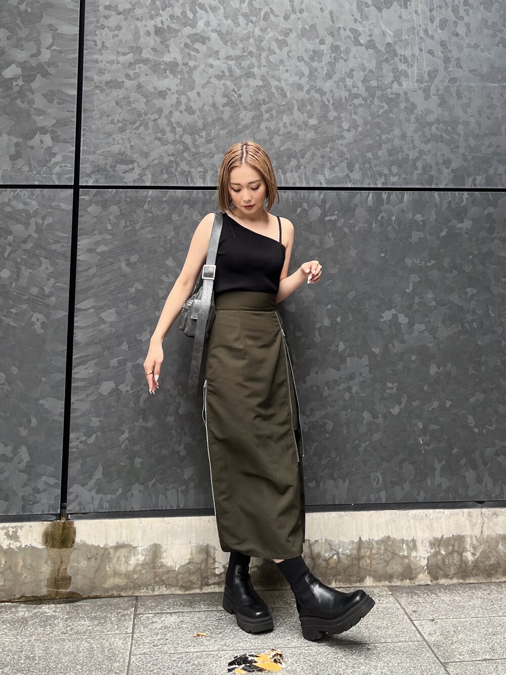 ブラック系のニット/セーター、グリーン系のスカート、グレー系のショルダーバッグを着用したレディースの夏コーディネートの4枚目の写真