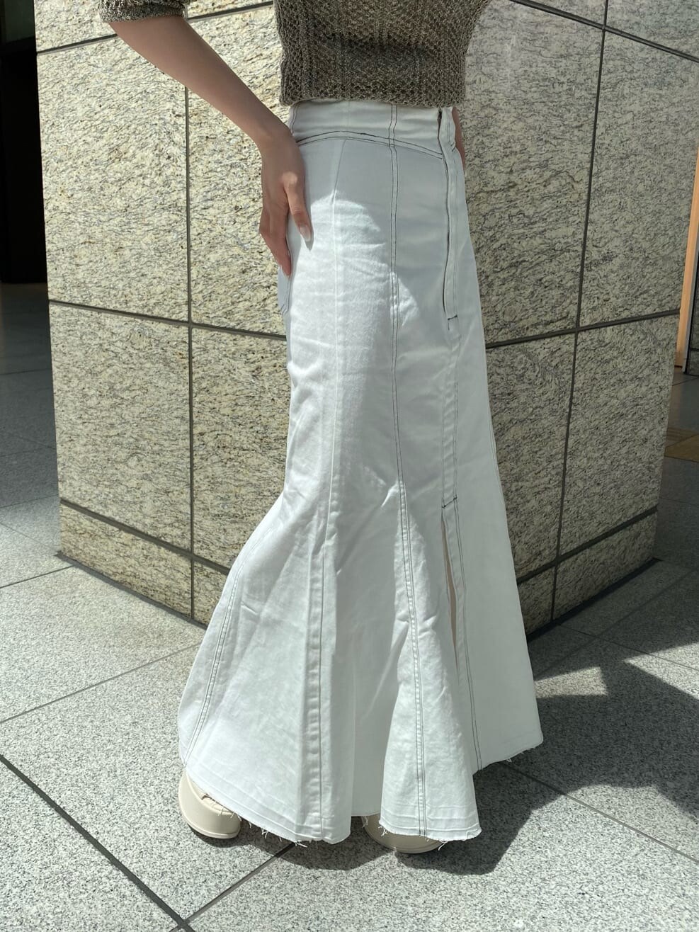 ホワイト系のキャミソール、ブラウン系のポロシャツ、ホワイト系のデニムスカートを着用したレディースの春コーディネートの7枚目の写真