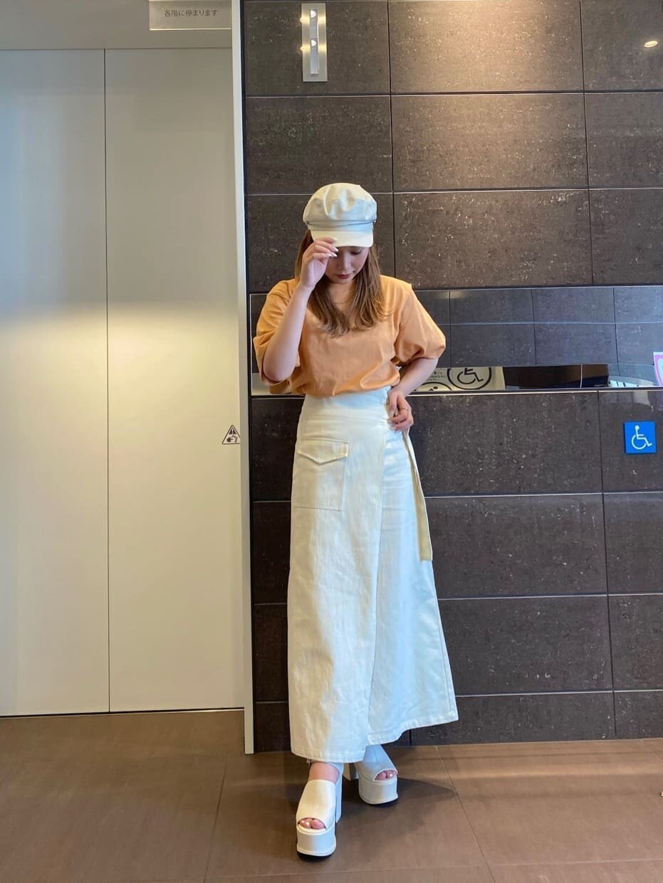 ホワイト系のスカート、オレンジ系のTシャツ/カットソー、ホワイト系のサンダルを着用したレディースの春コーディネートの3枚目の写真