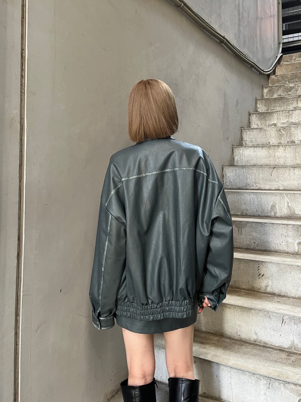 ブルー系のライダースジャケット、ブルー系のスカート、ブラック系のブーツを着用したレディースの夏コーディネートの7枚目の写真