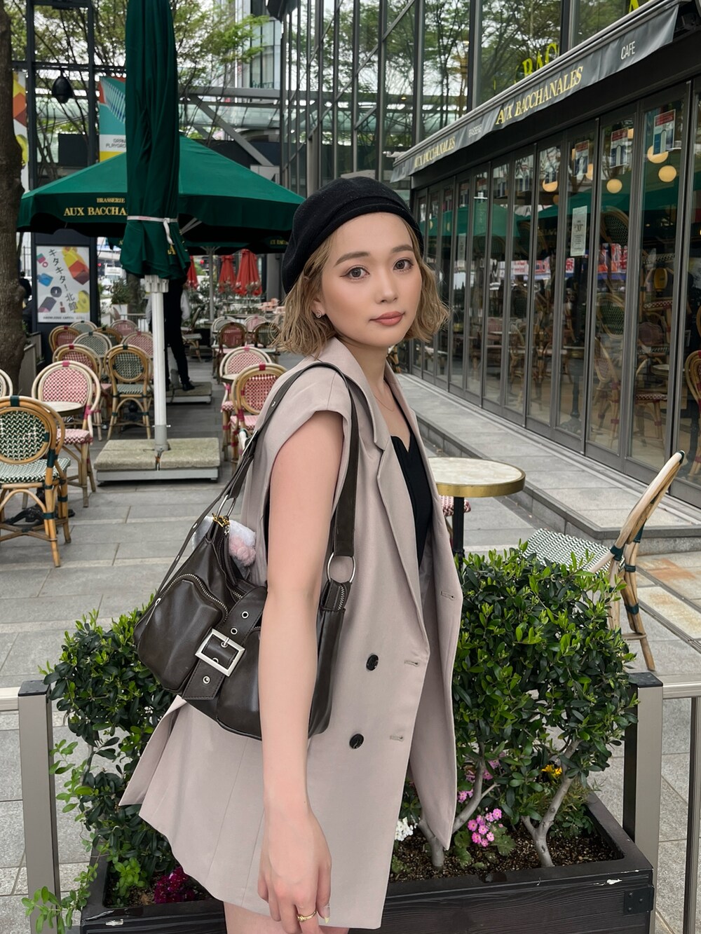 ブラック系のタンクトップ、ベージュ系のベスト、ブラウン系のハンドバッグを着用したレディースの春コーディネートの2枚目の写真