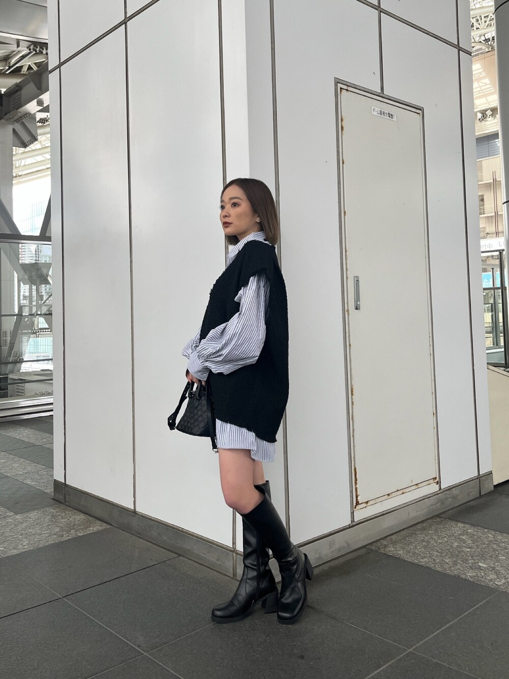 ブラック系のワンピース、ブラック系のハンドバッグ、ブラック系のブーツを着用したレディースの冬コーディネートの2枚目の写真