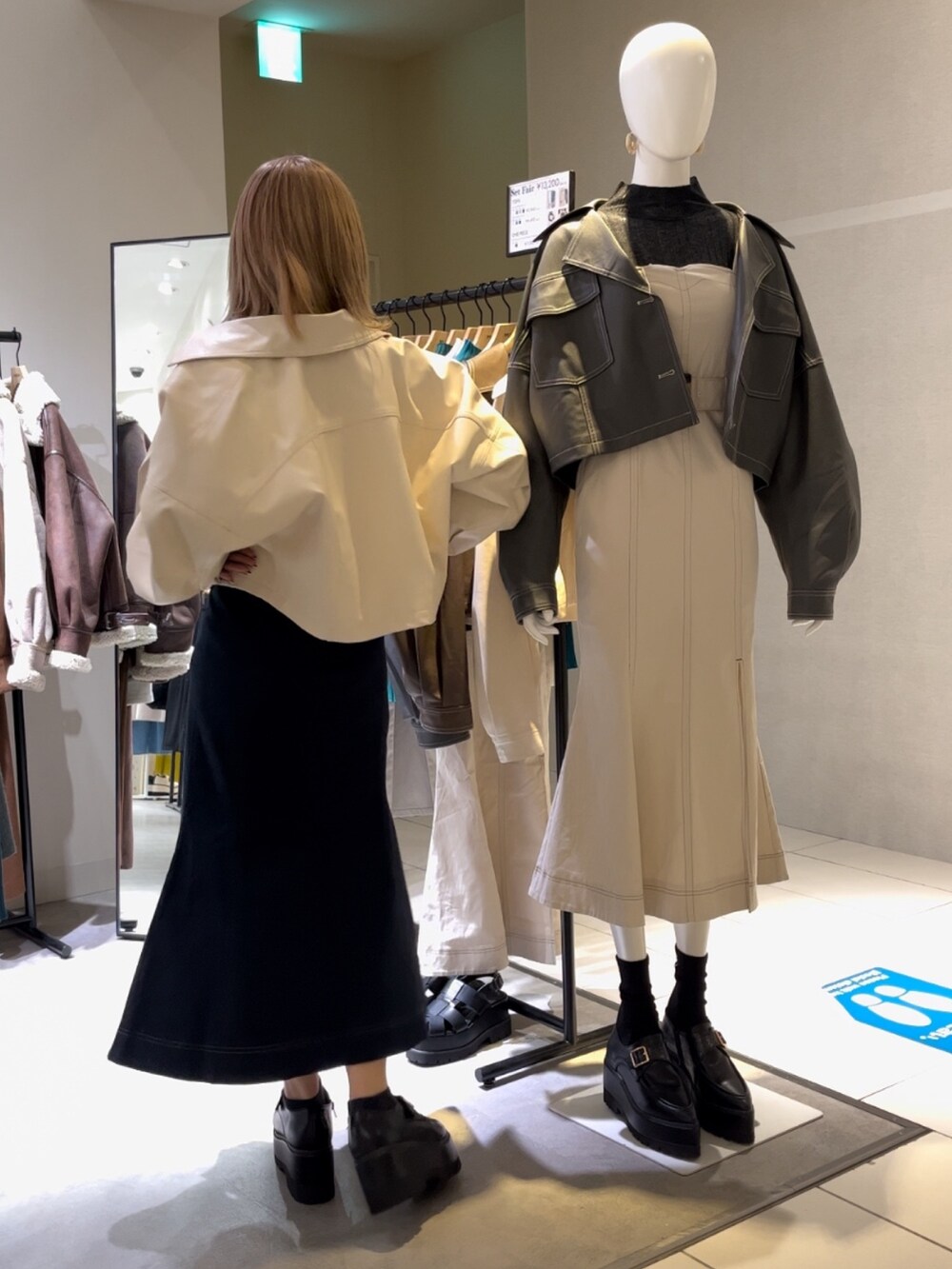 ブラック系のニット/セーター、ホワイト系のライダースジャケット、ブルー系のジャンパースカートを着用したレディースの冬コーディネートの2枚目の写真