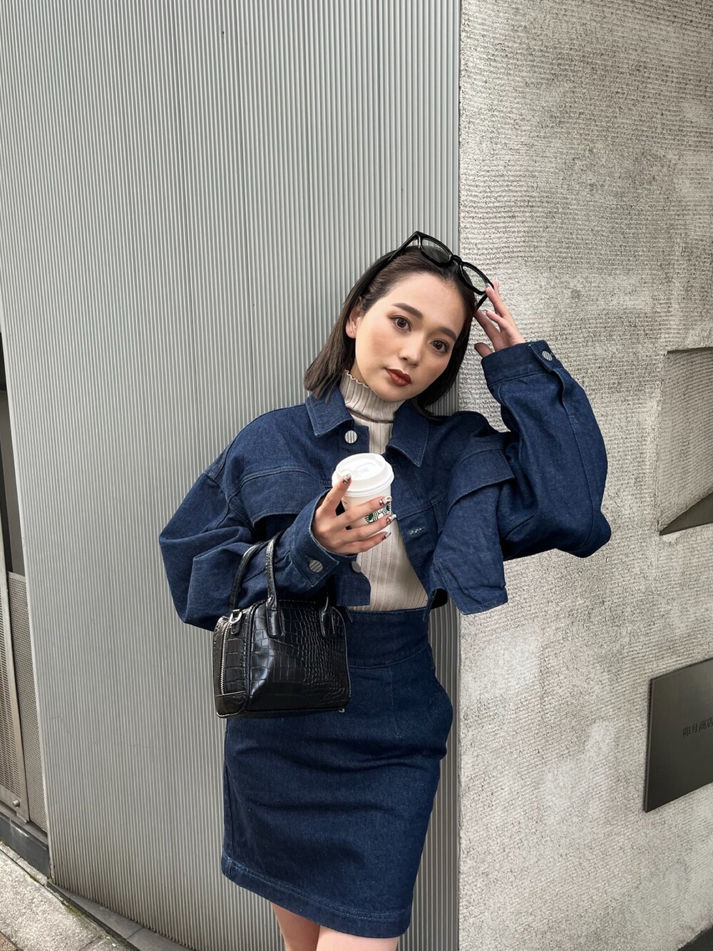 ブラック系のボストンバッグ、ブラック系のブーツ、ブルー系のデニムジャケットを着用したレディースの夏コーディネートの4枚目の写真