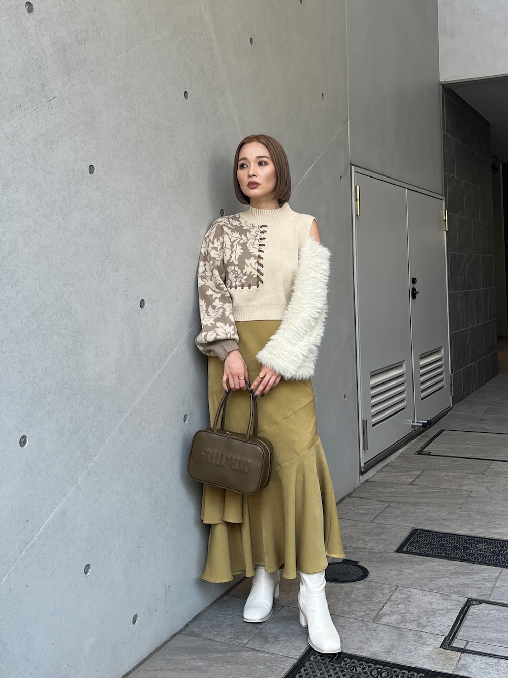 ホワイト系のニット/セーター、イエロー系のボストンバッグ、ホワイト系のブーツを着用したレディースの秋コーディネートの2枚目の写真
