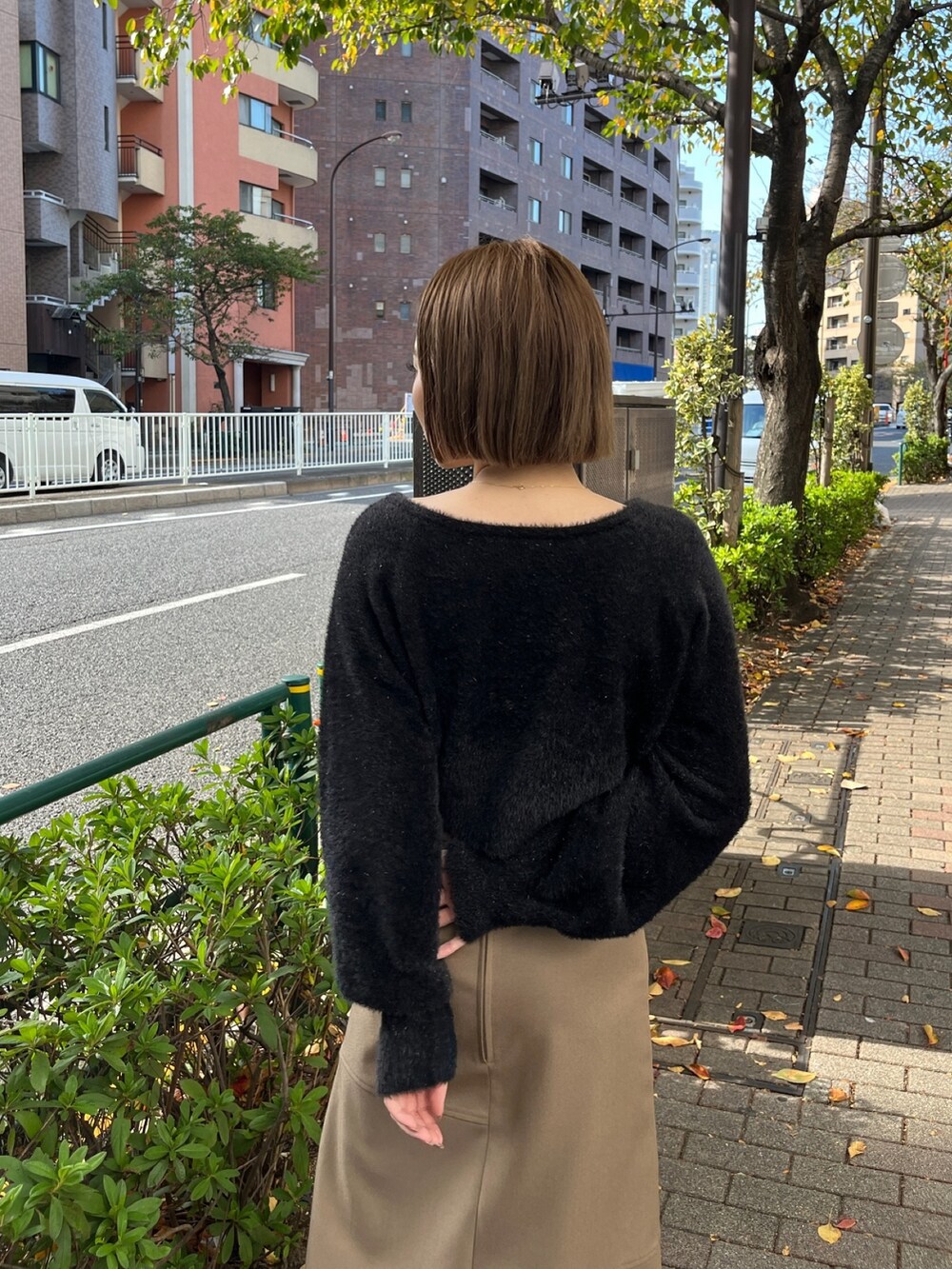 ブラック系のニット/セーター、ベージュ系のスカート、ブラック系のブーツを着用したレディースの秋コーディネートの4枚目の写真