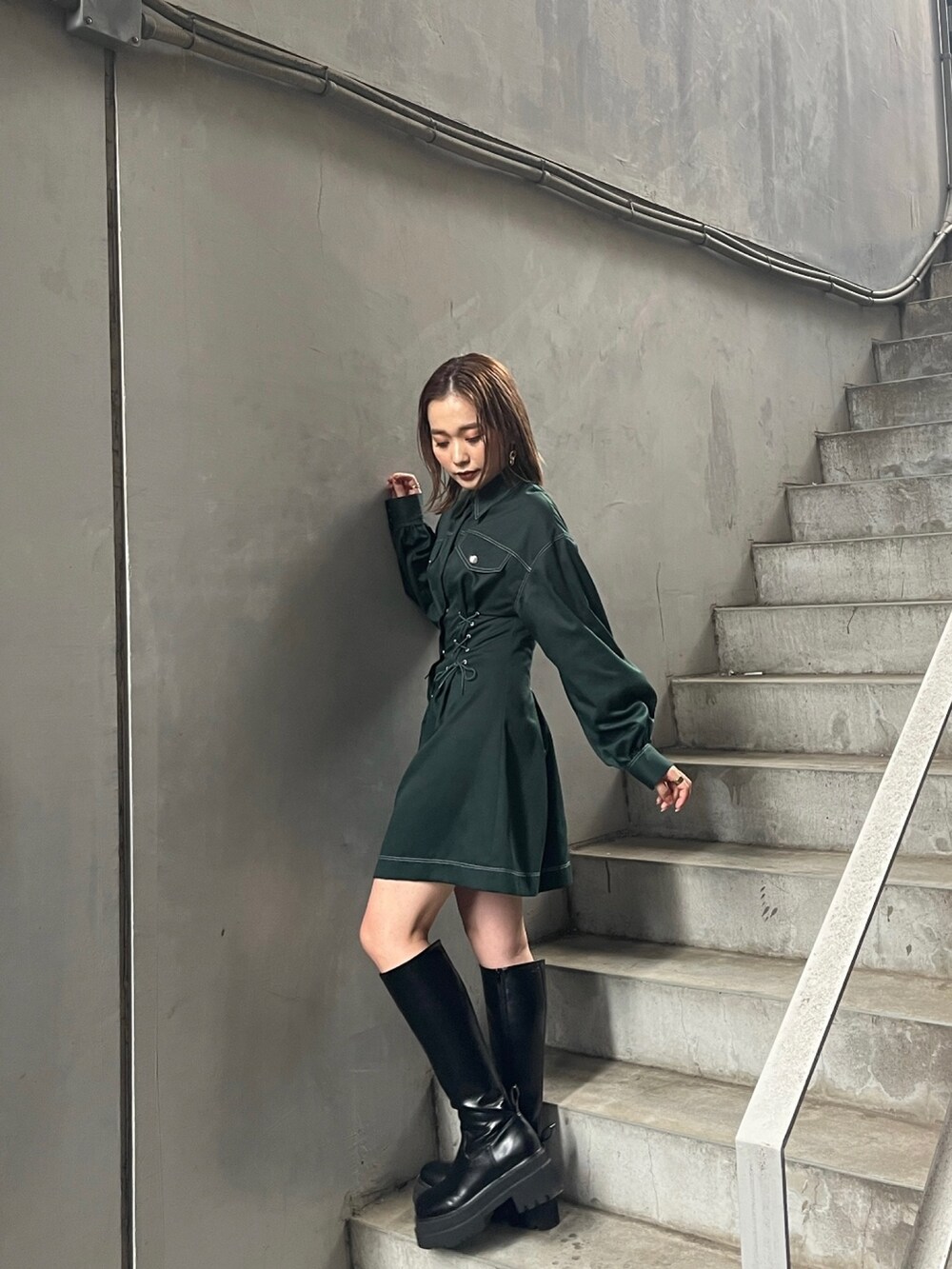 グリーン系のワンピース、ブラック系のブーツを着用したレディースの秋コーディネートの3枚目の写真