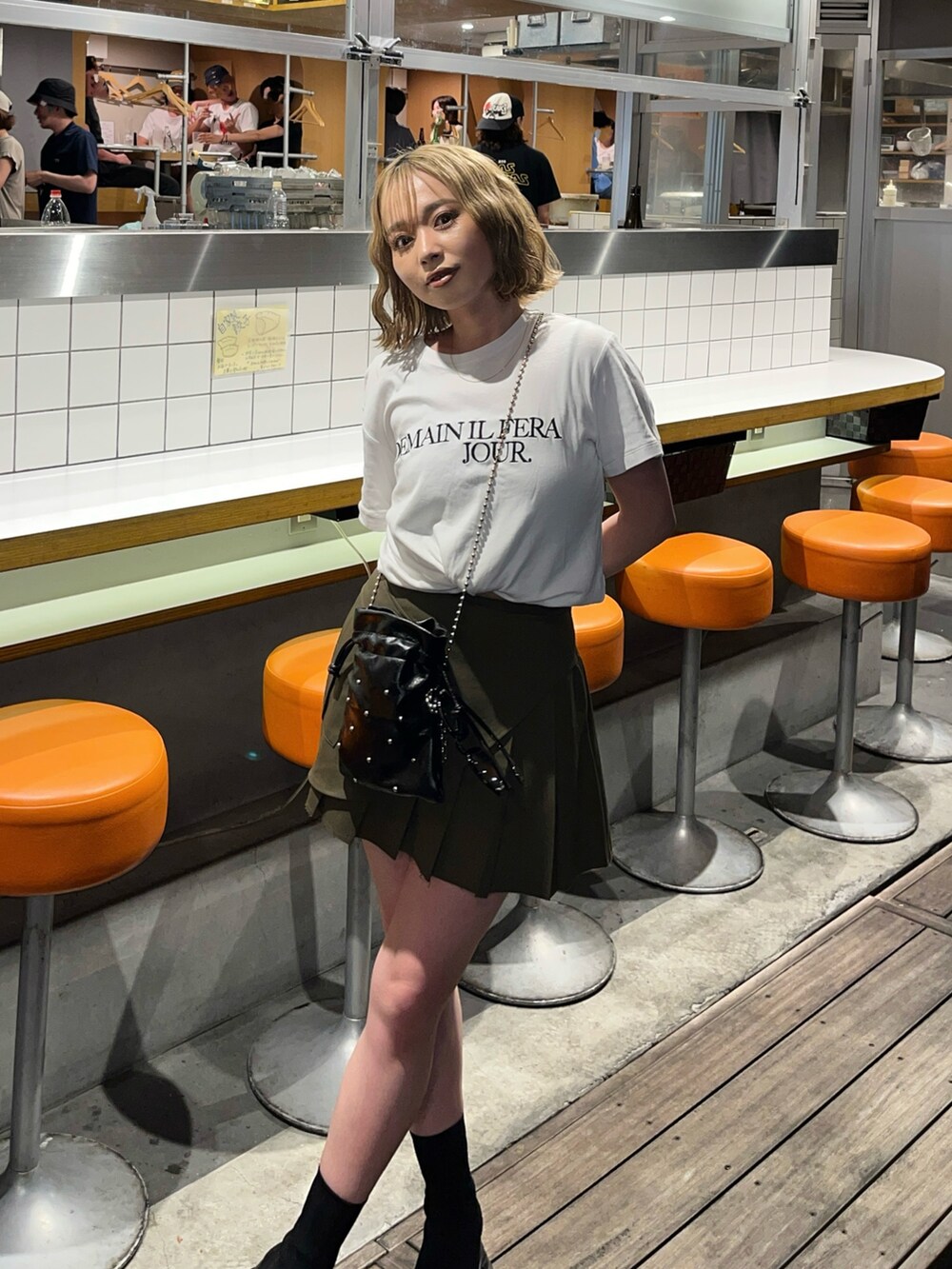 ブラック系のショルダーバッグ、グリーン系のスカートを着用したレディースの夏コーディネートの3枚目の写真