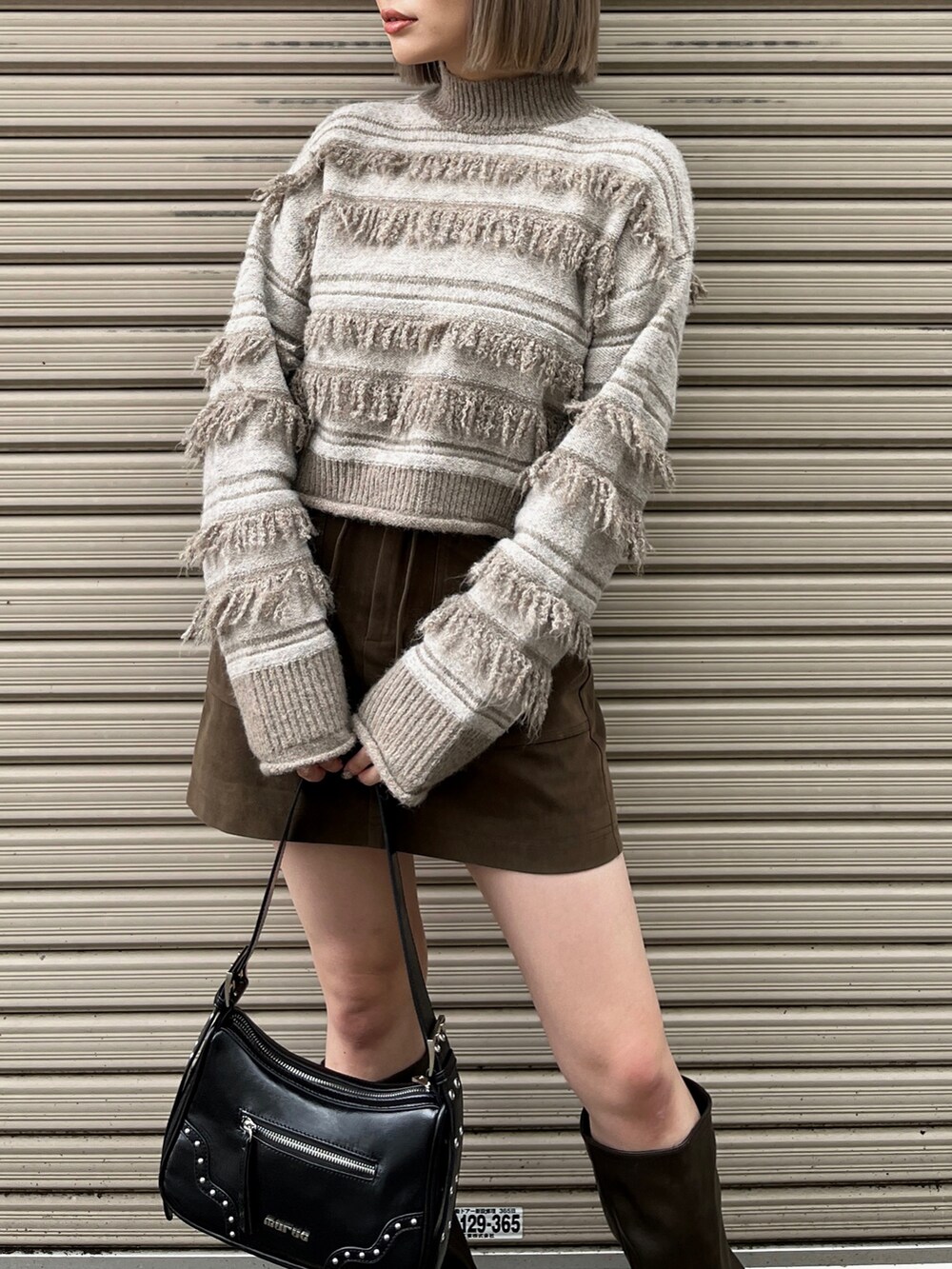 ホワイト系のニット/セーター、ブラック系のハンドバッグ、ブラウン系のスカートを着用したレディースの秋コーディネートの5枚目の写真