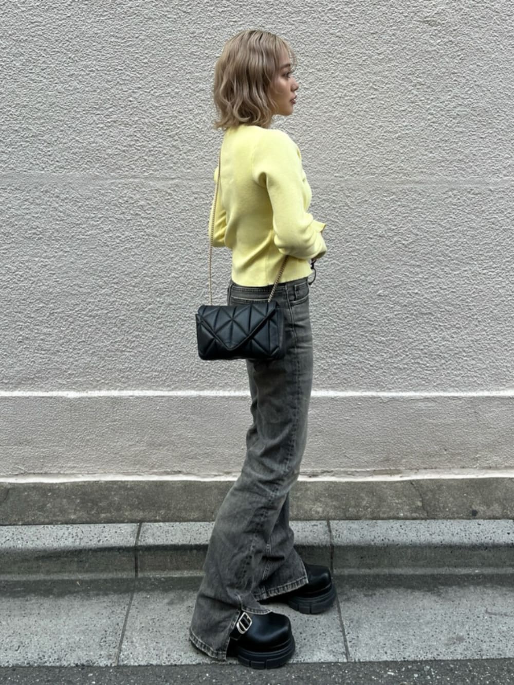 ブラック系のブーツ、イエロー系のニット/セーターを着用したレディースの春コーディネートの2枚目の写真