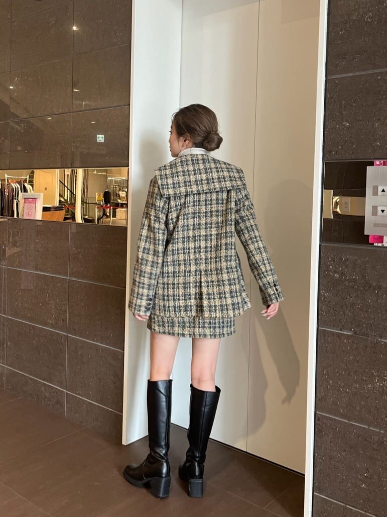 ブラック系のブーツ、ホワイト系のニット/セーター、グレー系のスカートを着用したレディースの秋コーディネートの4枚目の写真