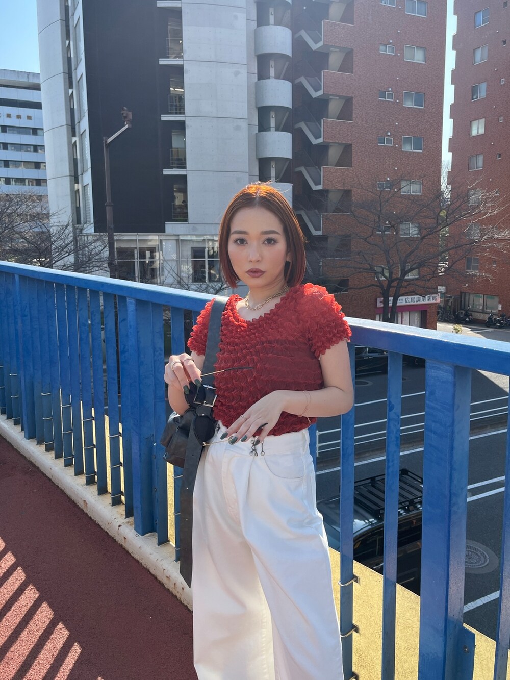 ホワイト系のデニムパンツ、ブラック系のショルダーバッグ、レッド系のシャツ/ブラウスを着用したレディースの春コーディネートの3枚目の写真