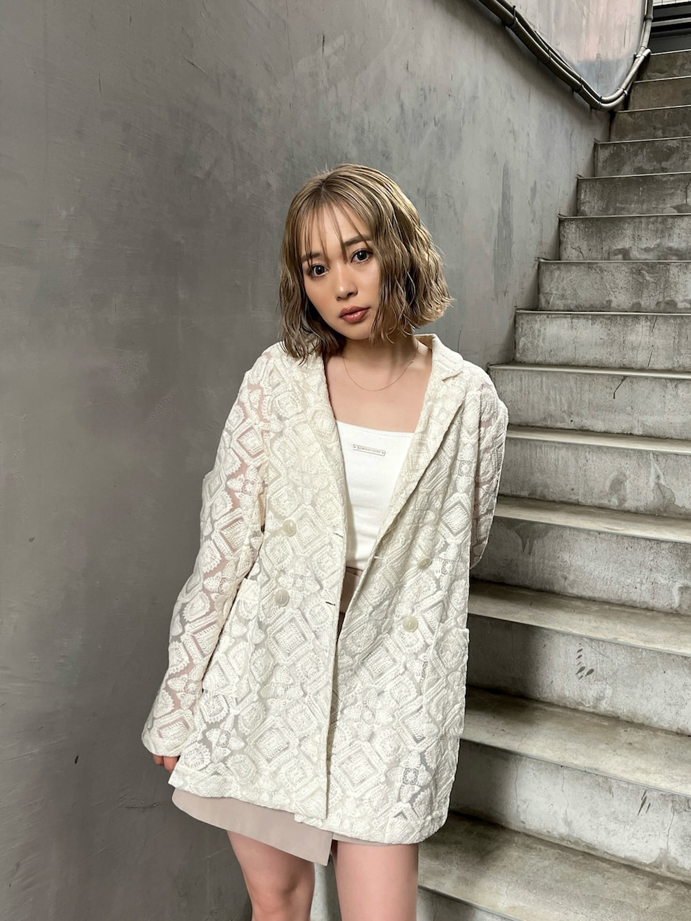 ホワイト系のテーラードジャケット、ホワイト系のキャミソール、ベージュ系のスカートを着用したレディースの春コーディネートの4枚目の写真