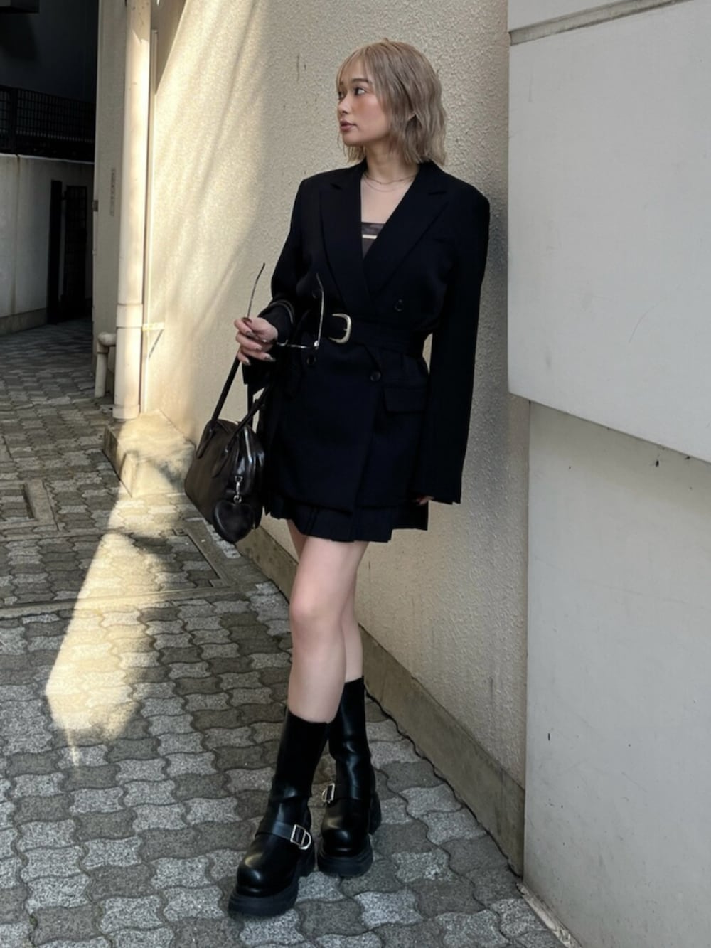 ブラック系のブーツ、ブラック系のテーラードジャケット、ブラウン系のキャミソールを着用したレディースの春コーディネートの3枚目の写真