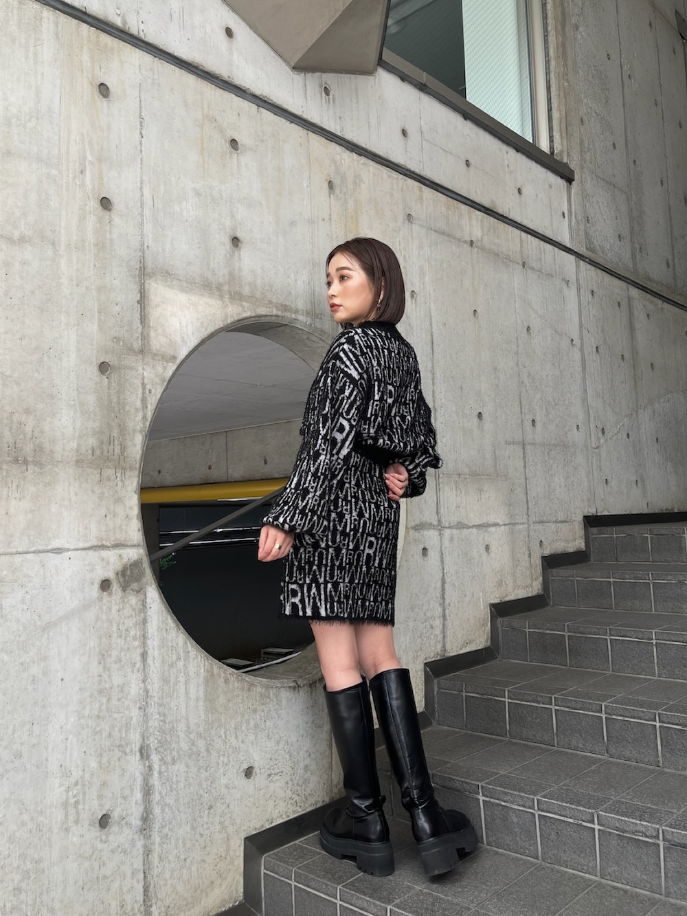 グレー系のダウンベスト、ブラック系のニット/セーター、ブラック系のスカートを着用したレディースの秋コーディネートの5枚目の写真