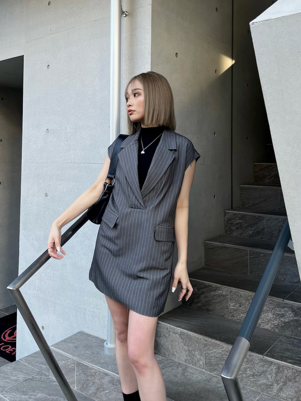 グレー系のワンピース、ブラック系のサンダル、ブラック系のニット/セーターを着用したレディースの夏コーディネートの3枚目の写真