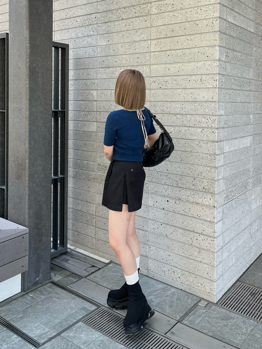 ブラック系のブーツ、ブラック系のスカート、ブルー系のニット/セーターを着用したレディースの春コーディネートの3枚目の写真