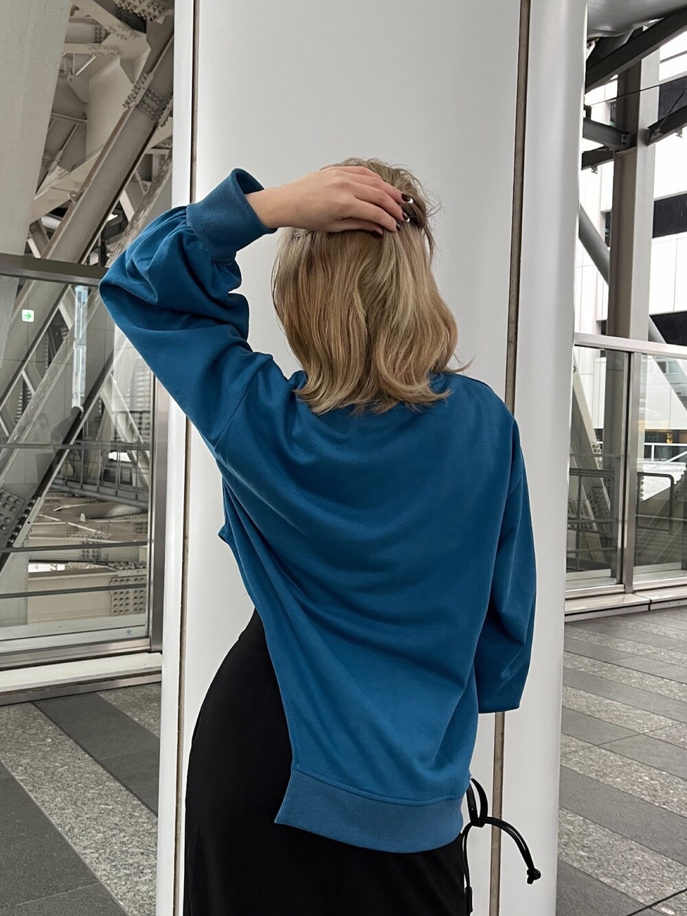 ブルー系のTシャツ/カットソー、ブラック系のスカート、ブラック系のハンドバッグを着用したレディースの冬コーディネートの6枚目の写真